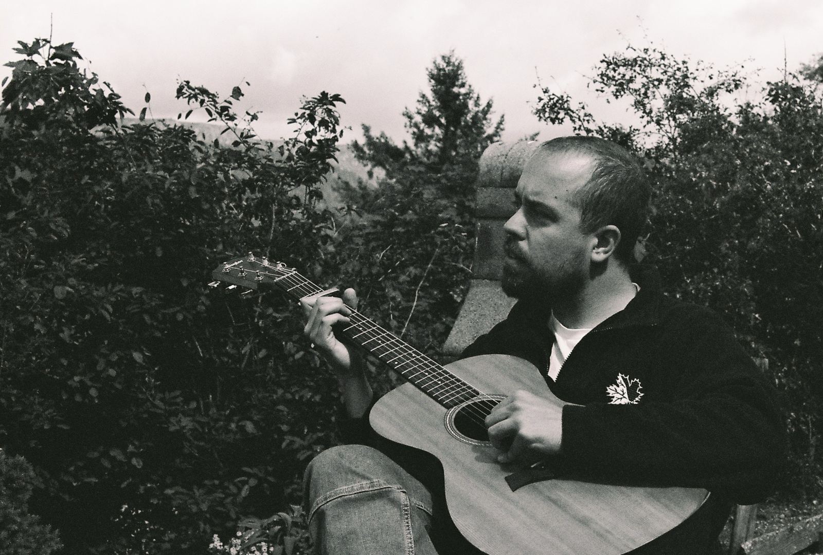 Rosán spielt Gitarre im Garten, Schwarzweißfoto